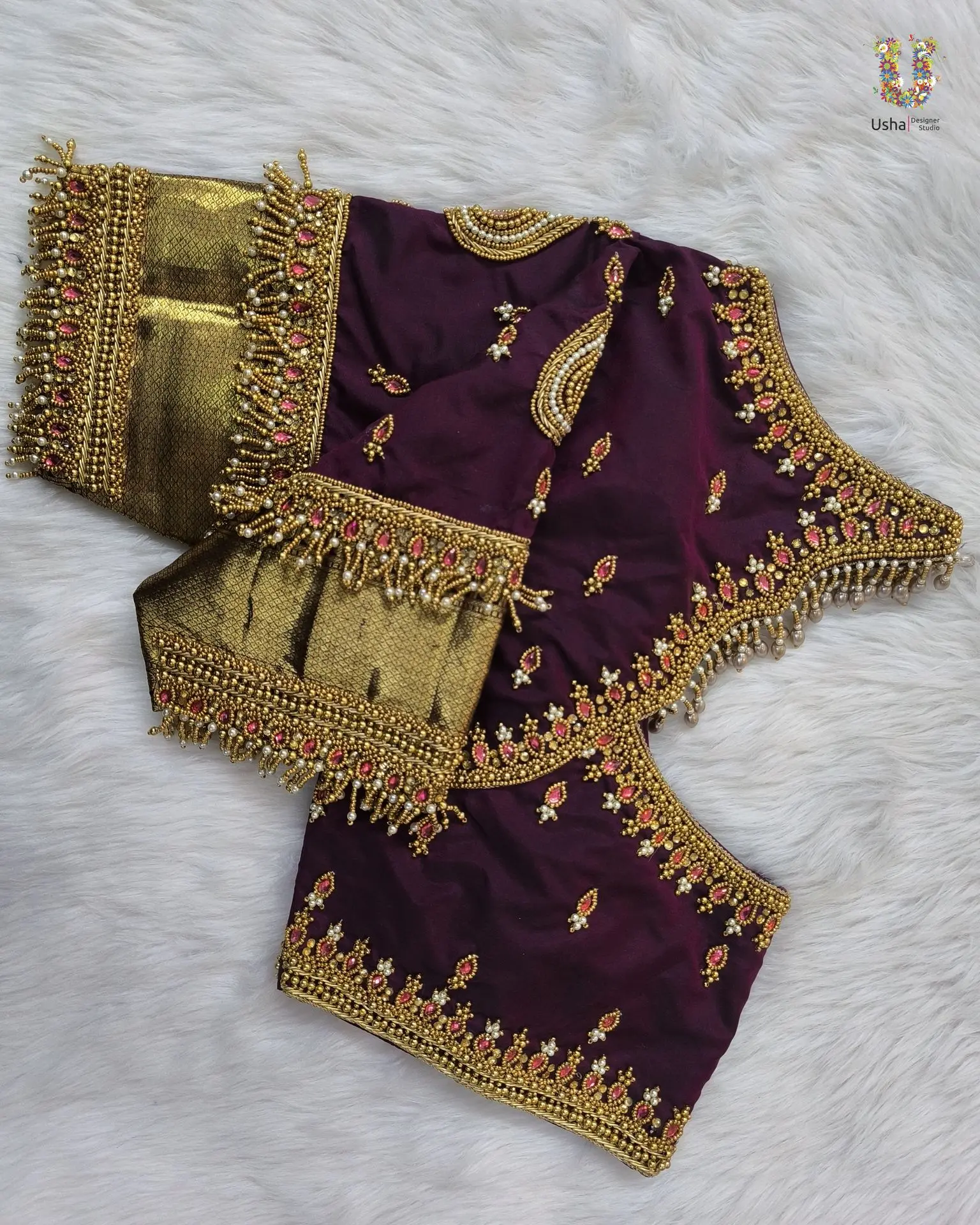Plum bridal blouse embellished with antique gold beadwork, pink stones, and pearl fringes, handcrafted by Usha Designer Studio