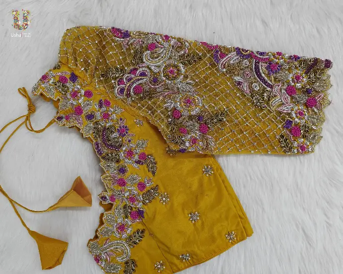 Mustard bridal blouse adorned with intricate silver, pink, and purple aari embroidery and floral net sleeve, by Usha Designer Studio