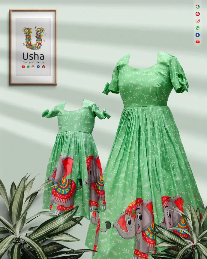 Mother and daughter in coordinated green long printed frocks from Usha Designer Studio, Vijayawada, featuring vibrant multicolour elephant motifs, scalloped U-necklines, pleated skirts, and heart-cut sleeves with charming bows—perfect for festive occasions and family celebrations.