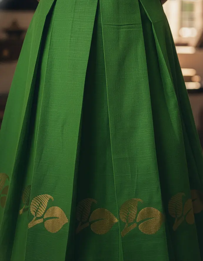 Green pattu kids frock with boat neckline, long sleeves, box pleats, and gold detailing, tailor-made by Usha Designer Studio, Vijayawada.