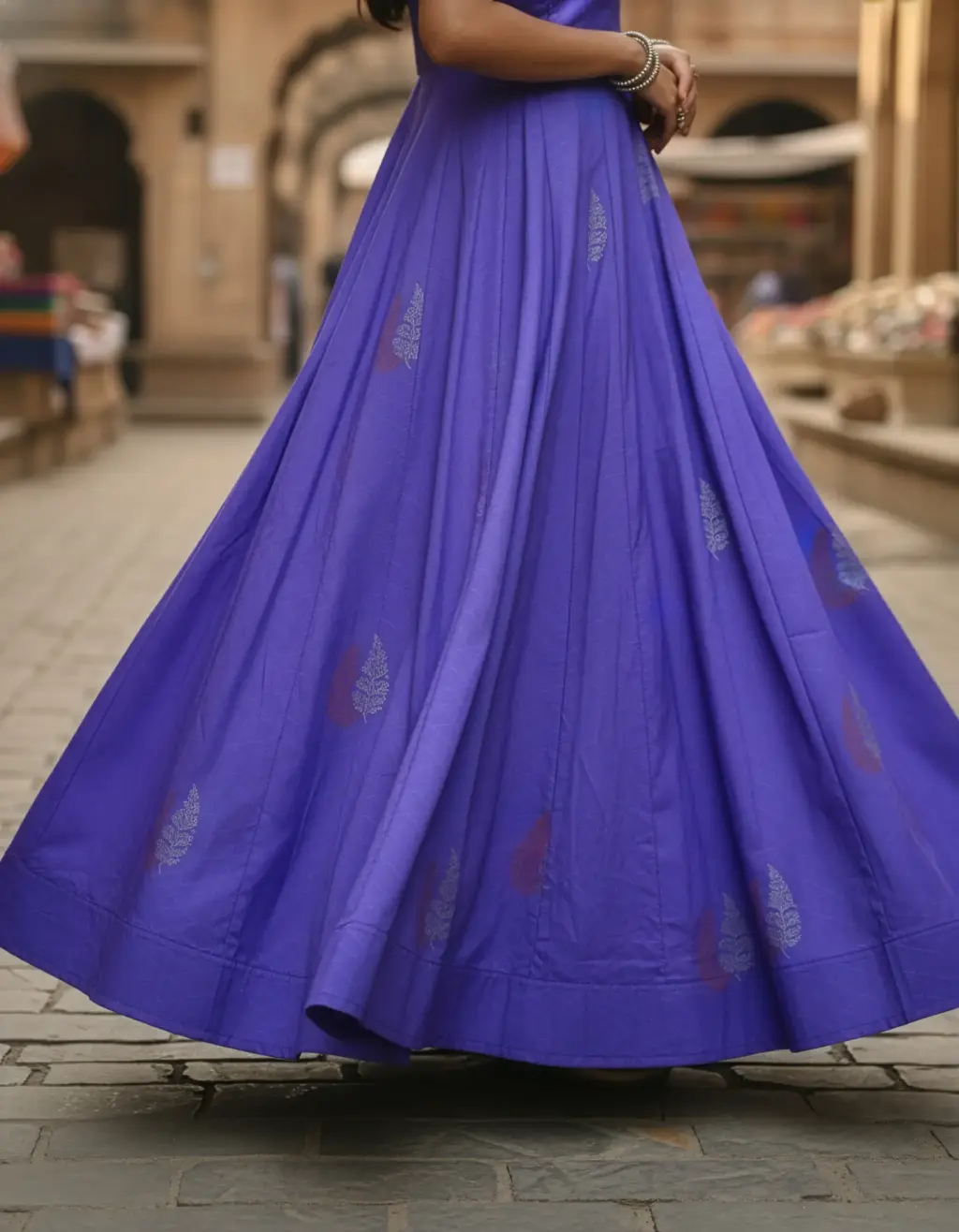 Full-length image of a tailor-made, vibrant purple silk long frock with a full Kalli cut Gera, a scalloped neckline, and elbow-length sleeves with scalloped edges. Upcycled from an heirloom saree by Usha Designer Studio, Vijayawada.