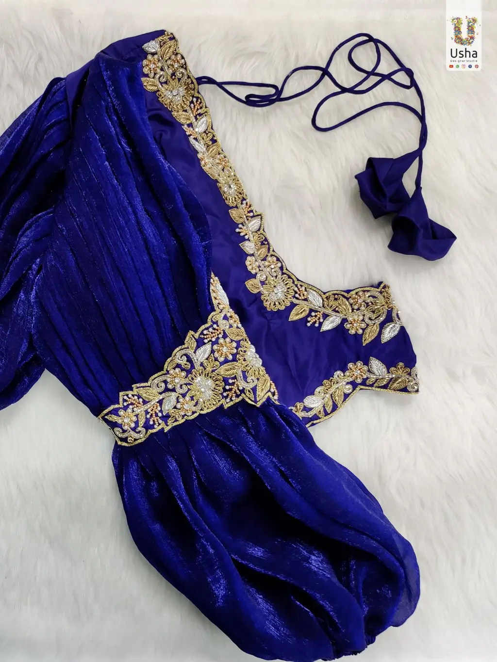 Royal blue bridal blouse featuring intricate gold Aari embroidery on the neckline, waist, and armlet, with elegant bracelet sleeves – Usha Designer Studio, Vijayawada Royal Blue Bridal Aari Work Blouse with Bracelet Sleeves – Exclusive Designer Piece by Usha Designer Studio, Vijayawada