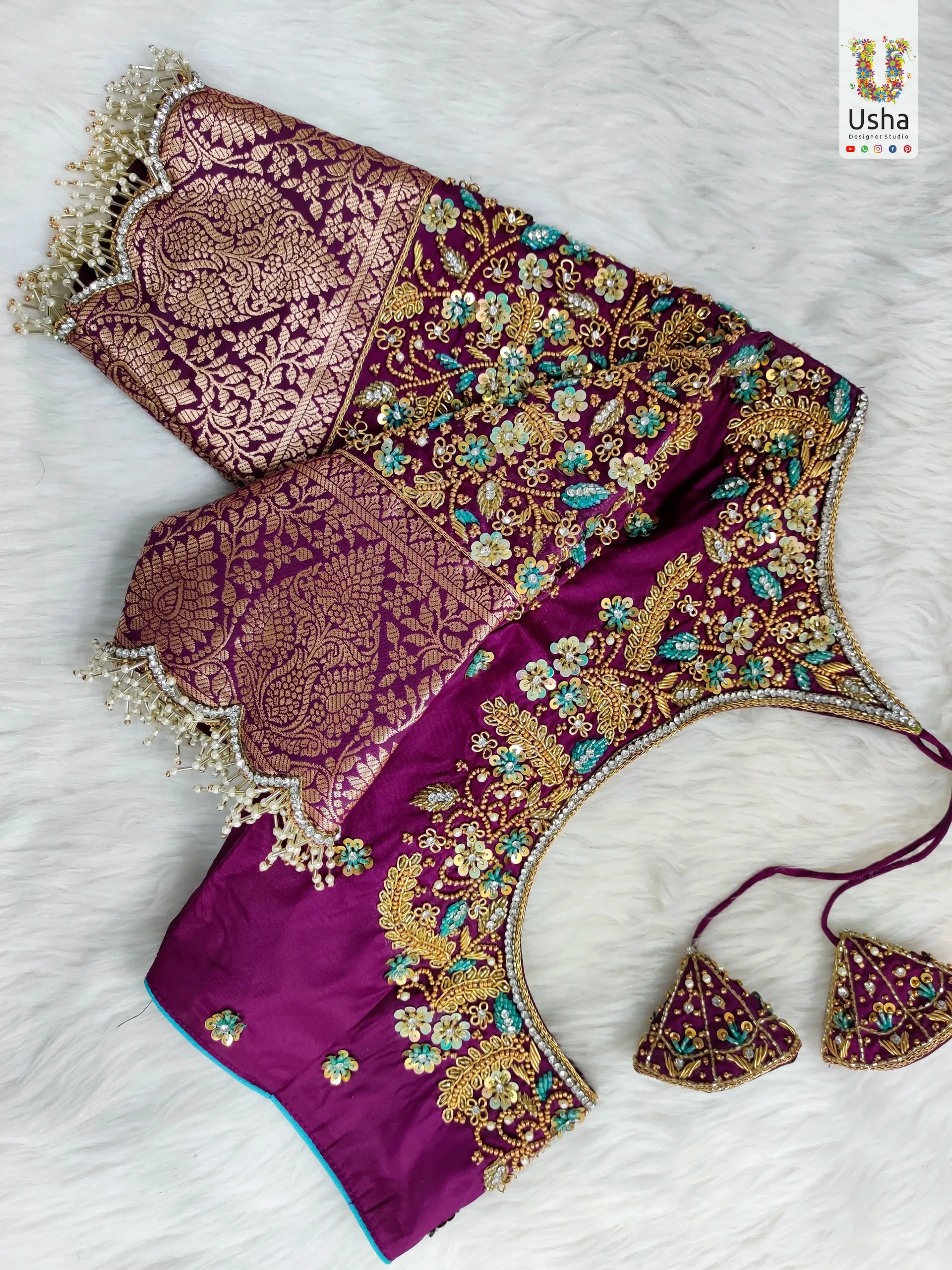 Tailor-Made Floral All Over Aari Embroidery Bridal Blouse | Usha Designer Studio Vijayawada Tailor-made magenta bridal blouse with intricate gold floral Aari embroidery, Banarasi sleeve detailing, and handcrafted beaded tassels by Usha Designer Studio Vijayawada.
