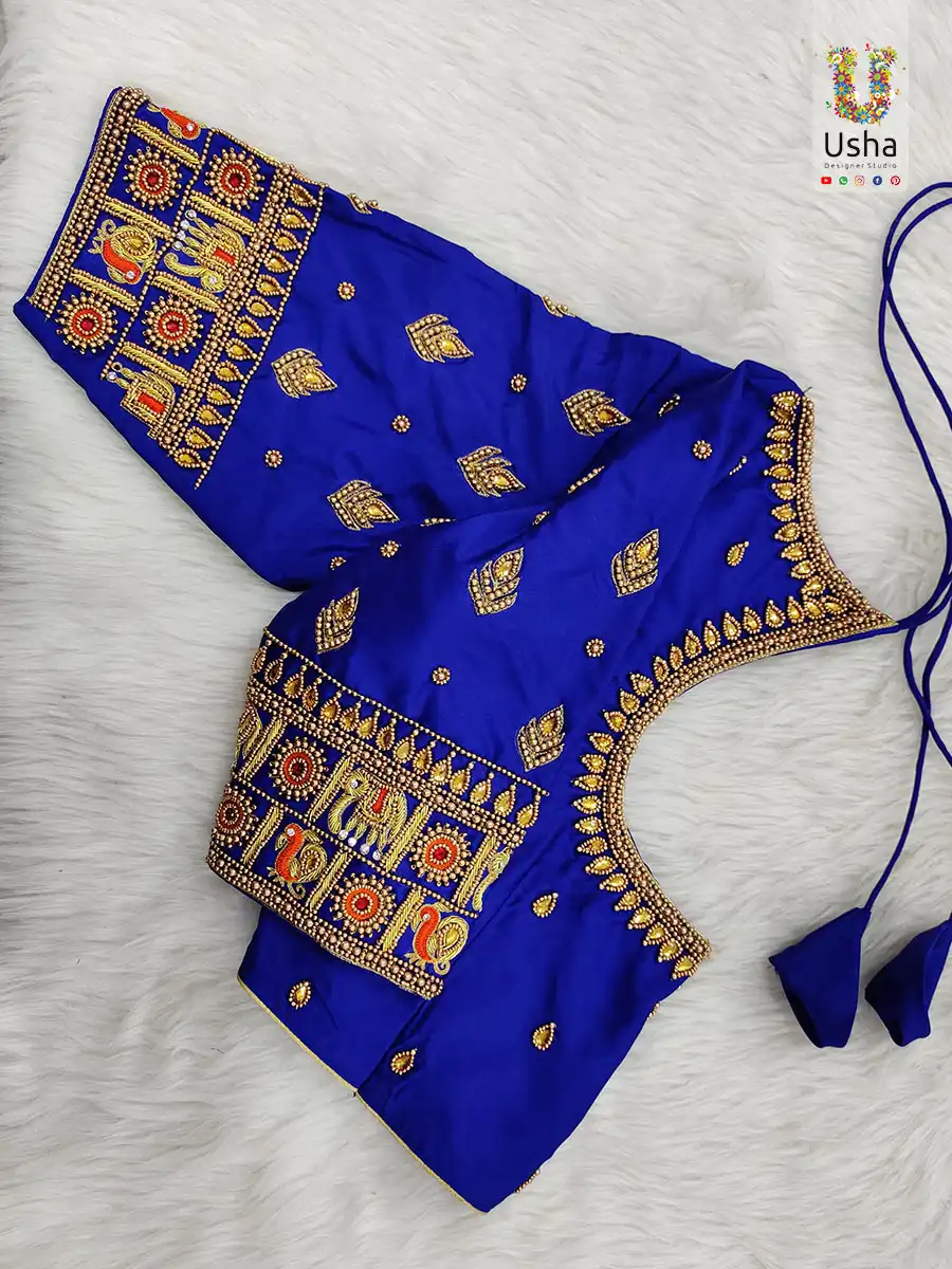 Royal blue silk bridal blouse featuring intricate gold Aari embroidery, heritage elephant motifs, and scalloped neckline by Usha Designer Studio, Vijayawada.