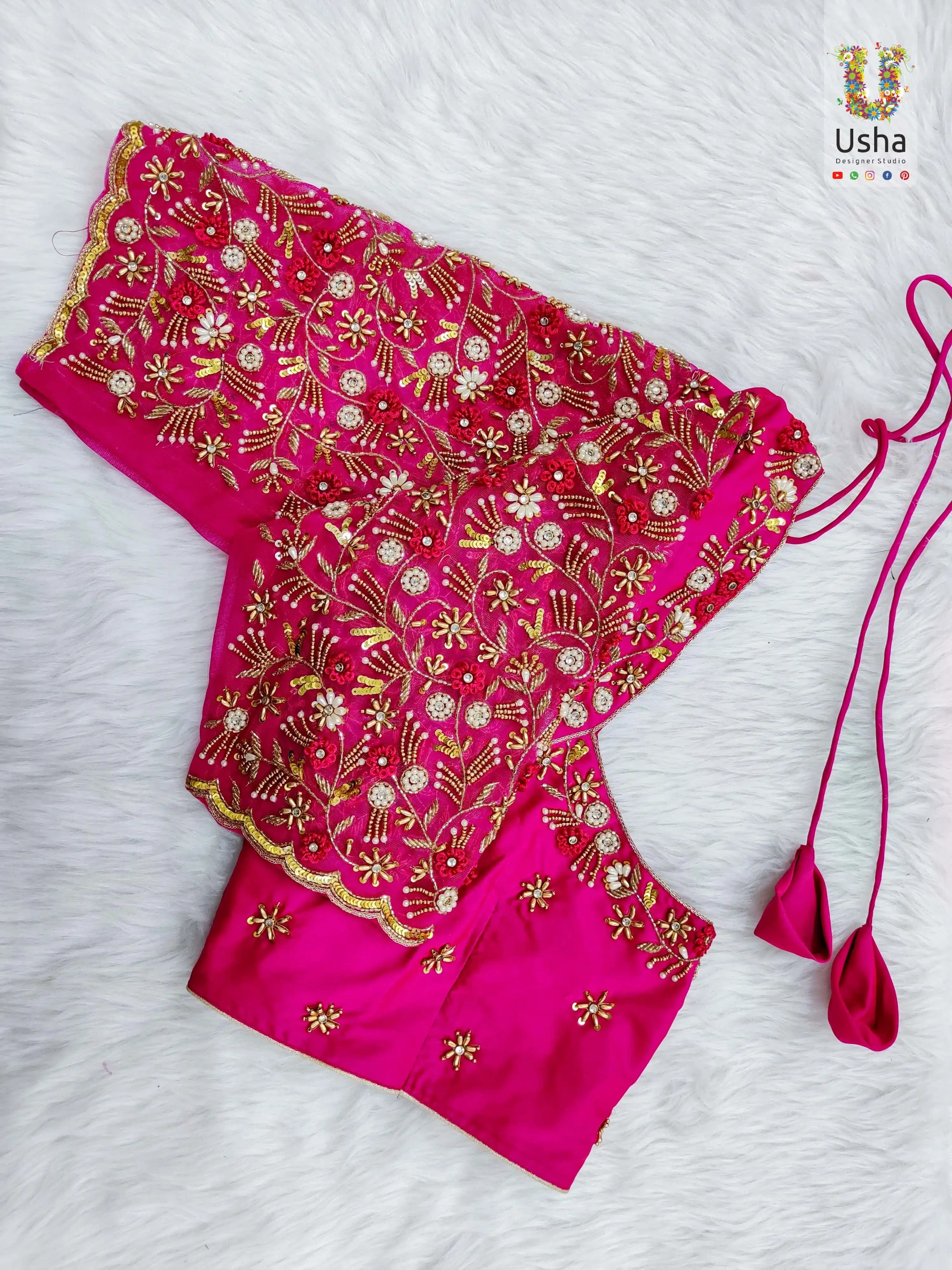 Magenta pink bridal blouse with heavy hand embroidery, floral zardosi work, pearl details, and scalloped sleeves by Usha Designer Studio Vijayawada.